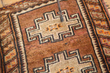 Geometric barber pole border with tangerine orange and brown tribal motifs on the vintage mat.
