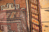 Geometric corner and barber pole border detail of a vintage Oushak rug in tangerine and burgundy.