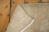 Visible hand-knotted foundation and secured side of a sandy beige vintage Oushak rug.