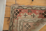 Vintage Oushak rug's blush rose pink field with floral motifs, showing hand-knotted pile texture.
