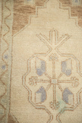 Vintage Oushak rug with ornate light brown and blue-grey motifs on a sand field.
