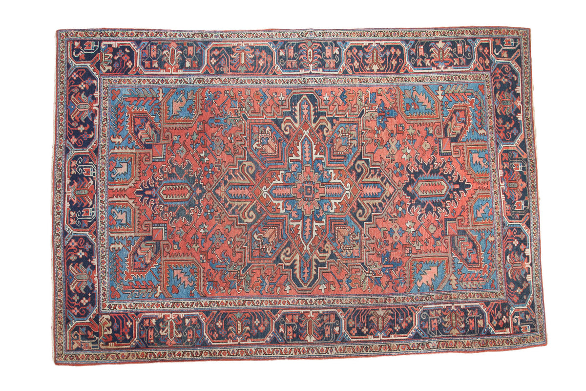 Vintage Persian Heriz rug, geometric brick red field, sky blue medallion with rams horn motifs, navy borders, 6'9" x 9'11".