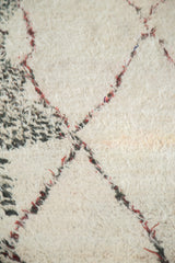 Plush shorn ivory wool with wine red outlines and charcoal black speckles.