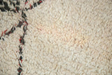 Plush shorn ivory wool pile texture with charcoal and wine red pattern accents.