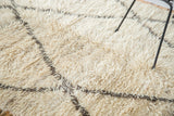 Plush ivory wool pile of a vintage Moroccan Berber rug with charcoal lattice outlines.