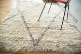 Plush, shaggy ivory wool pile detail with charcoal geometric lattice pattern.