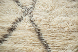 Thick, plush, shaggy ivory wool pile of a Moroccan Berber rug with charcoal grey lattice outlines.
