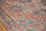 Hand-knotted distressed Heriz rug detail with faded brick red field and sky blue tendrils.