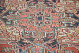 Distressed Heriz rug detail with brick red field, geometric rams horn, and hook-like blue motifs.