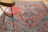 Distressed Heriz rug texture with softened brick red and blue geometric floral patterns.
