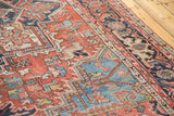 Distressed Heriz carpet showing textured brick red field with sky blue geometric and floral motifs.