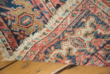Secure ivory fringe and distressed Heriz carpet showing brick red and blue border patterns.