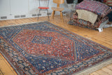 Vintage Shiraz rug corner: indigo pawn design border, madder red field, and new fringe.