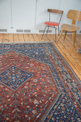 Angled view of vintage Shiraz tribal carpet, intricate pinwheel motifs in madder red and indigo.