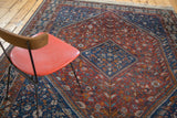 Southwestern tribal Shiraz carpet with madder red field, indigo medallion, pinwheel motifs.