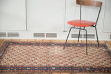 Distressed corner of Malayer rug, textured ivory field, madder red pattern, indigo border.