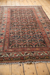 Distressed Kurdish rug, diamond lattice, floral motifs, rust, green, charcoal tones, even pile wear.