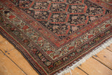 Distressed hand-knotted Kurdish rug corner, rich rust and moss green floral borders, light fringe.