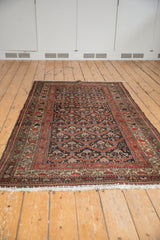 Clean white fringe and rust red border on a secured end of a distressed rug.