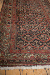 Distressed vintage Kurdish rug's fringe and lower border, showing floral patterns and even wear.