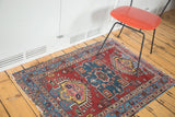 Colorful distressed Heriz rug with a geometric medallion in brick red, teal, and saffron.