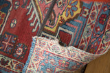 Flipped corner of a distressed Heriz rug displaying its colorful hand-knotted weave and low pile.