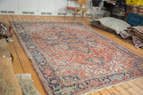 Vintage Heriz carpet corner with geometric florals, rams horn motifs, brick red, and indigo.