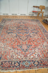 Vintage Heriz carpet detail: geometric floral patterns in brick red, indigo, and blue, with fringe.