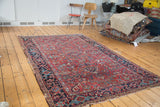 Vintage Heriz rug's left border, featuring geometric curvilinear patterns in brick red, navy, and teal.