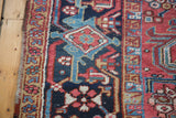 Vintage Heriz carpet: geometric border with brick red, navy, and teal motifs.