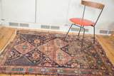 Distressed Afshar rug with tribal serrated lattice pattern, bronze, mallard green tones, tattered ends.