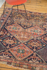 Distressed Persian Afshar rug with colorful serrated lattice panels, tribal florals, and tattered fringe.