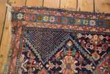 Distressed Afshar rug corner with tattered fringe and serrated tribal field pattern.