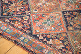 Distressed Afshar rug detail: tribal floral motifs, serrated panels, and terracotta-blue border.