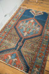 Intricate geometric herati motifs in indigo, rust, and coppery green on a distressed antique rug.