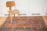 Distressed antique Kazak tribal rug, madder red field, and blue pawn design borders.
