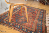 Distressed antique Kazak tribal rug; madder red field with ribboned blue borders and pawn design motifs.