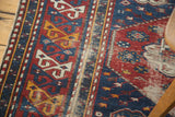 Distressed antique Shirvan rug border, rhythmic geometric patterns in saffron, ivory, and deep blue.