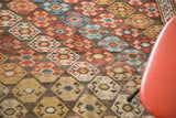 Distressed pile of antique Shirvan rug with rhythmic hexagonal medallions in red, blue, and saffron gold.