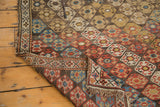 Shirvan rug corner folded, revealing hand-knotted weave, distressed hexagonal pattern, fringe.