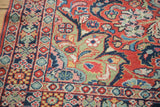 Vintage Arak Sarouk rug corner revealing ornate floral borders and a red field with green vines.