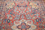 Curvilinear floral pattern on vintage Sarouk rug: cherry red, royal blue, blush, lime green, copper.