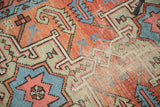 Time-softened geometric motifs in blush, light blue, and pale green, with visible exposed foundation.