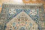 Serrated medallion and germinating flowers on vintage Abadeh rug's pale peach field in blue and brown.