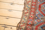 Antique Northwest Persian rug's worn selvage and geometric border in red, blue, and beige tones.
