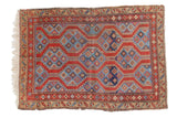 Antique Northwest Persian rug with madder root red field and geometric indigo blue diamond patterns.