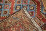 Red and blue geometric pile of a Northwest Persian rug, brown foundation, and fringe.