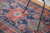 Distressed pile showcasing rich indigo blue and cherry red Heriz geometric patterns.