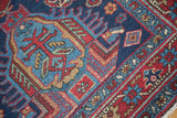 Distressed Heriz rug detail: geometric patterns, star border, deep indigo, cherry red.