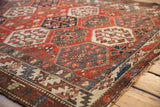 Distressed Baktiari rug showing hexagonal panels with blossoming florals in red, blue, and blush tones.